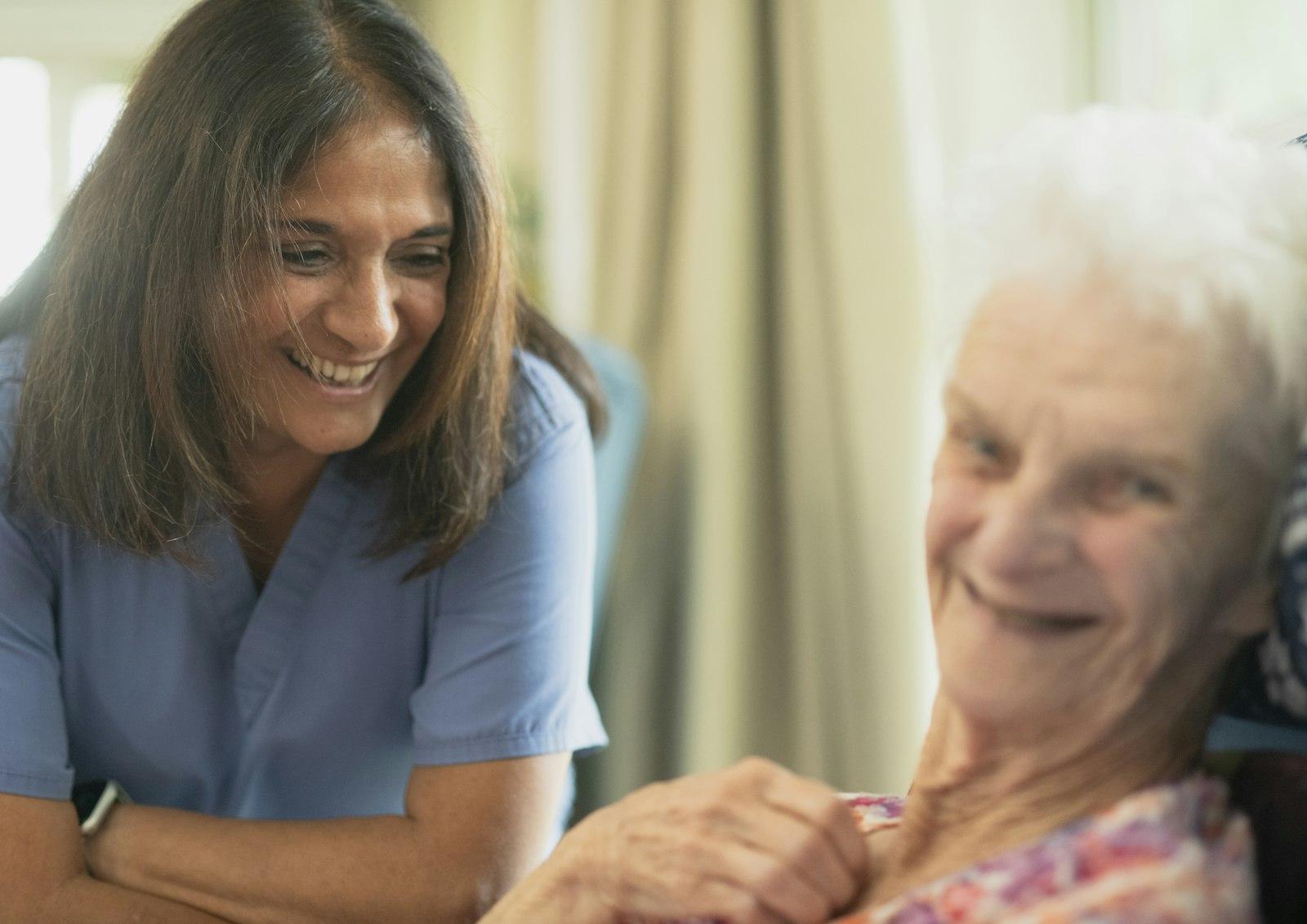 Une soignante souriante auprès d'une résidente